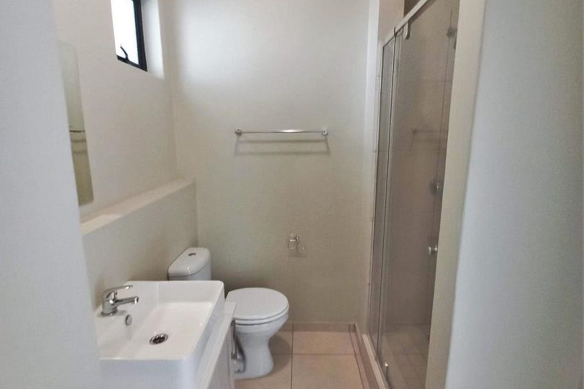 A clean and functional bathroom featuring a modern vanity, a glass-enclosed shower, and neutral floor tiling.