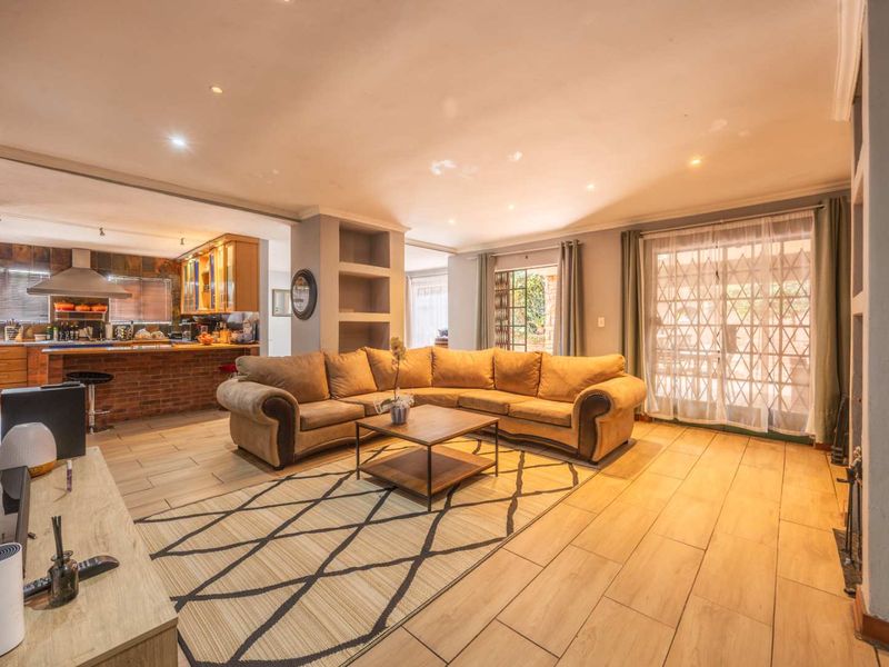 Spacious open-plan living area featuring tiled floors, recessed lighting, built-in shelving, and seamless flow into a well-appointed kitchen with a breakfast bar.