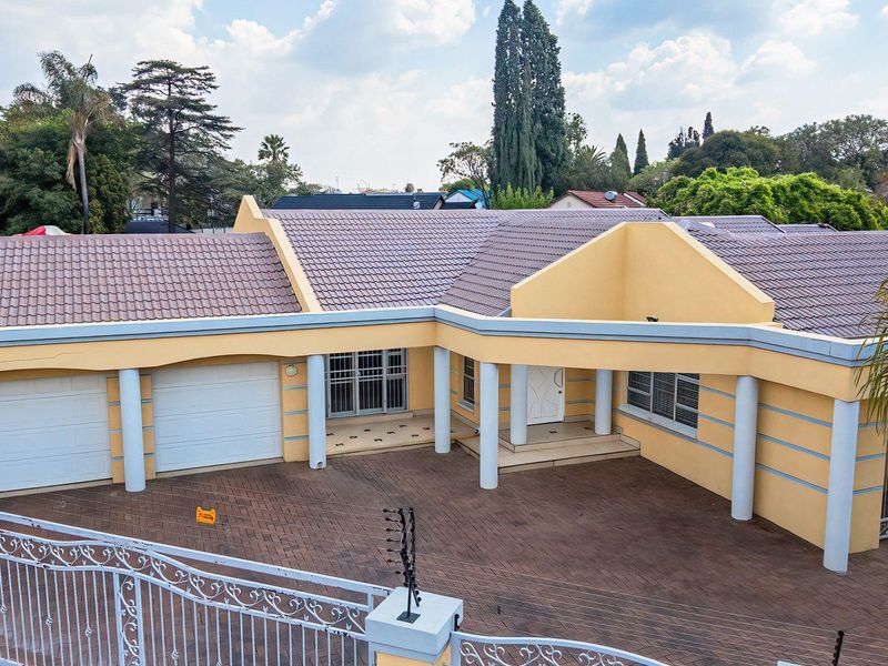Front elevation of a residential house featuring a paved driveway, double garage, covered entrance, and secure perimeter fencing.