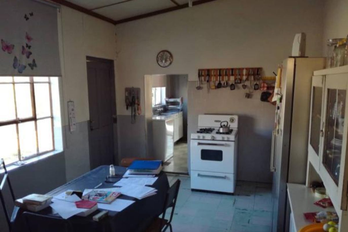 A functional kitchen area featuring a freestanding stove, tiled splashbacks, and an adjacent scullery space with direct access to the main kitchen area.