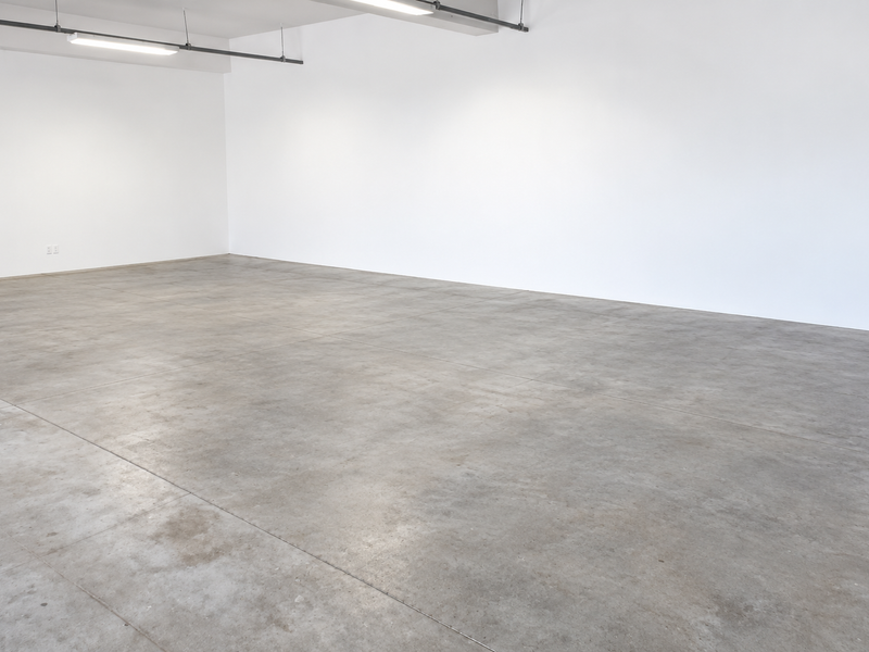 A spacious, open-plan industrial utility area featuring polished concrete flooring, clean white walls, and modern overhead strip lighting.