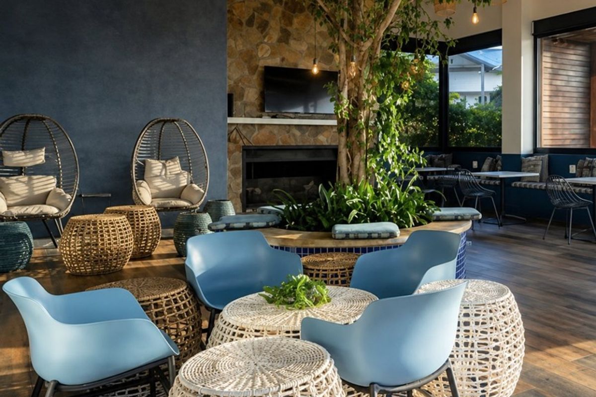A stylish, open-plan living area featuring a stone fireplace, exposed timber rafters, and a unique central indoor planter feature with integrated seating.