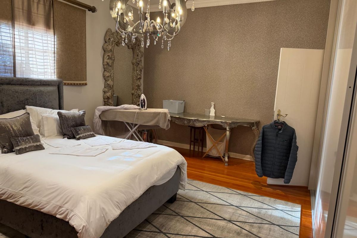 A well-maintained bedroom featuring hardwood flooring, crown molding, and recessed lighting, offering a comfortable and classic living space.