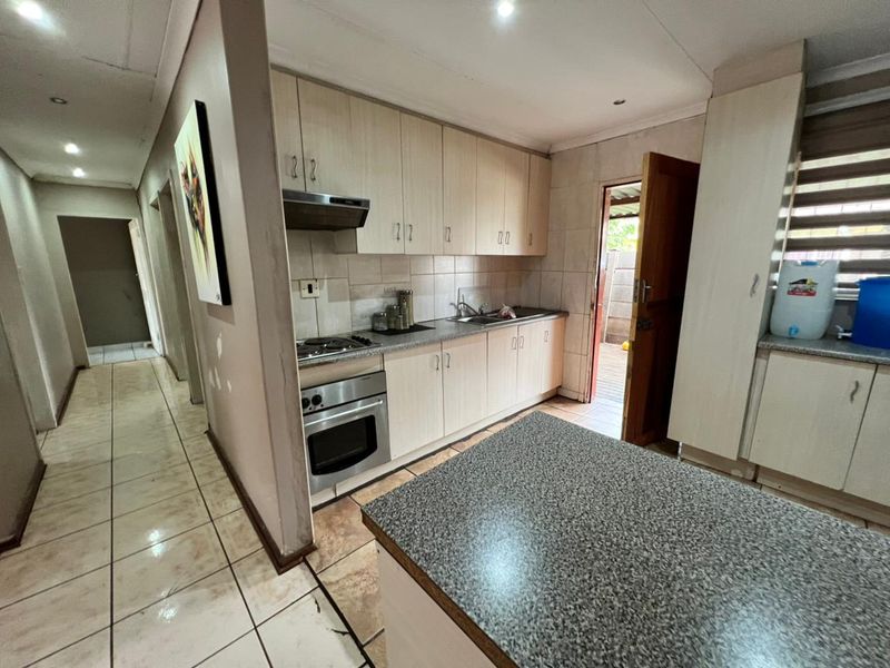 Functional kitchen featuring light wood-finish cabinetry, granite-look laminate countertops, built-in oven with gas hob, and direct access to the rear exterior.