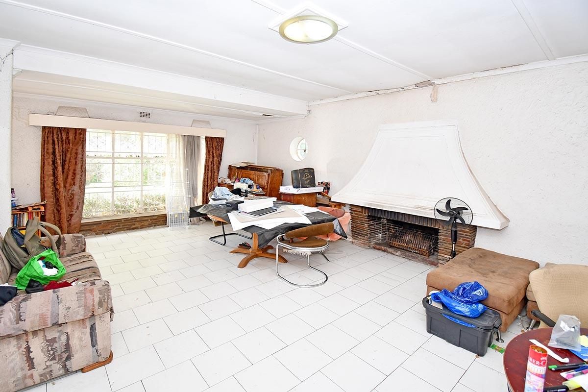 Spacious living room featuring a large built-in fireplace with a decorative mantle, tiled flooring, and ample natural light from the front-facing window.