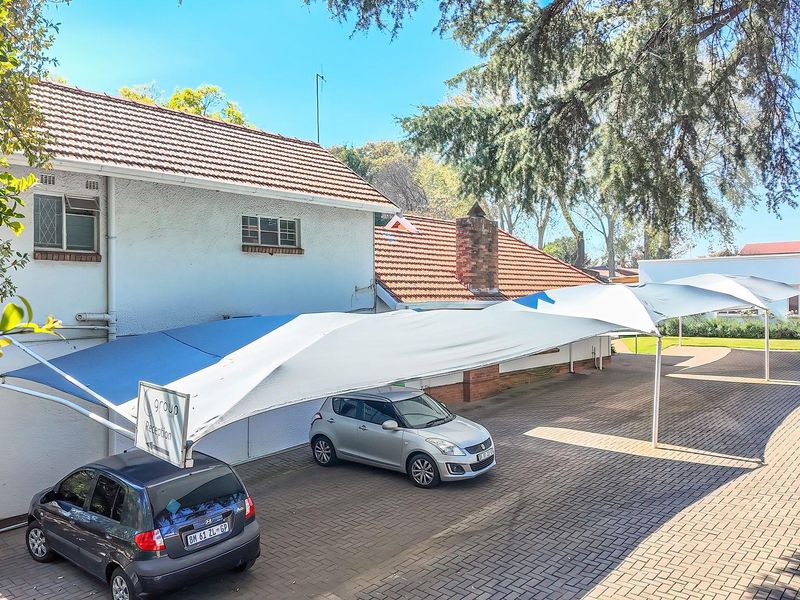 Exterior view of the office property featuring a paved driveway and a large shade sail carport structure.