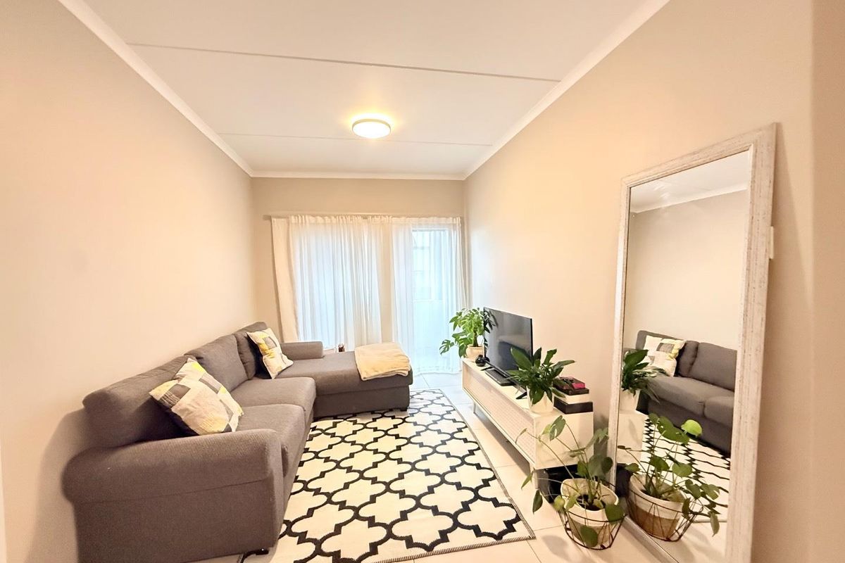 A bright and neutral living room featuring tiled flooring and a sliding glass door that provides access to the outdoor area.