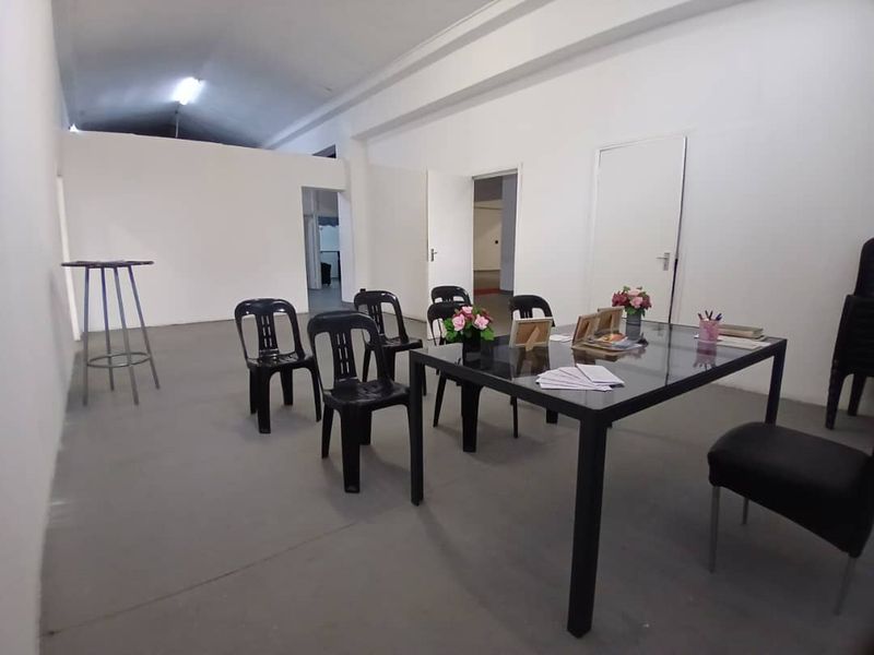 A functional office space featuring a vaulted ceiling, neutral walls, and multiple internal access points, suitable for a variety of business configurations.