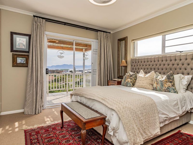 A well-maintained bedroom featuring built-in cupboards, a ceiling fan, and a sliding glass door providing access to a balcony with scenic views.