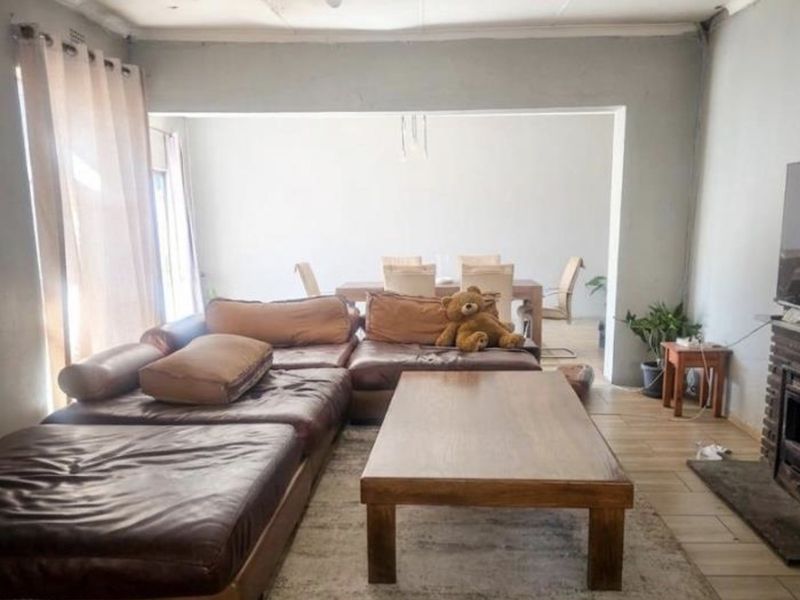 Open-plan living and dining area featuring tiled flooring and a fireplace, offering a spacious layout with potential for modernization.