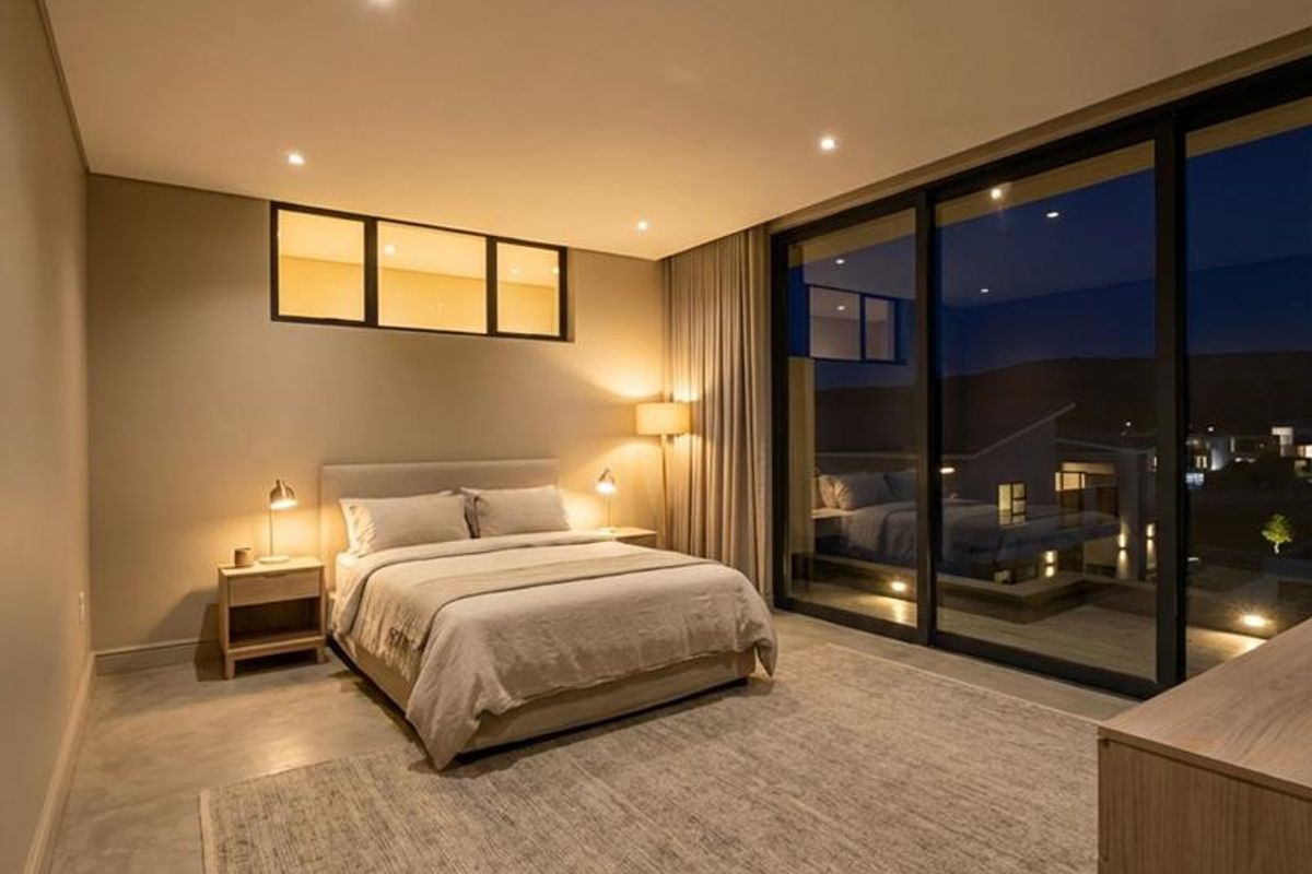 Modern bedroom featuring polished concrete floors, recessed lighting, and large sliding glass doors that open to an outdoor area.