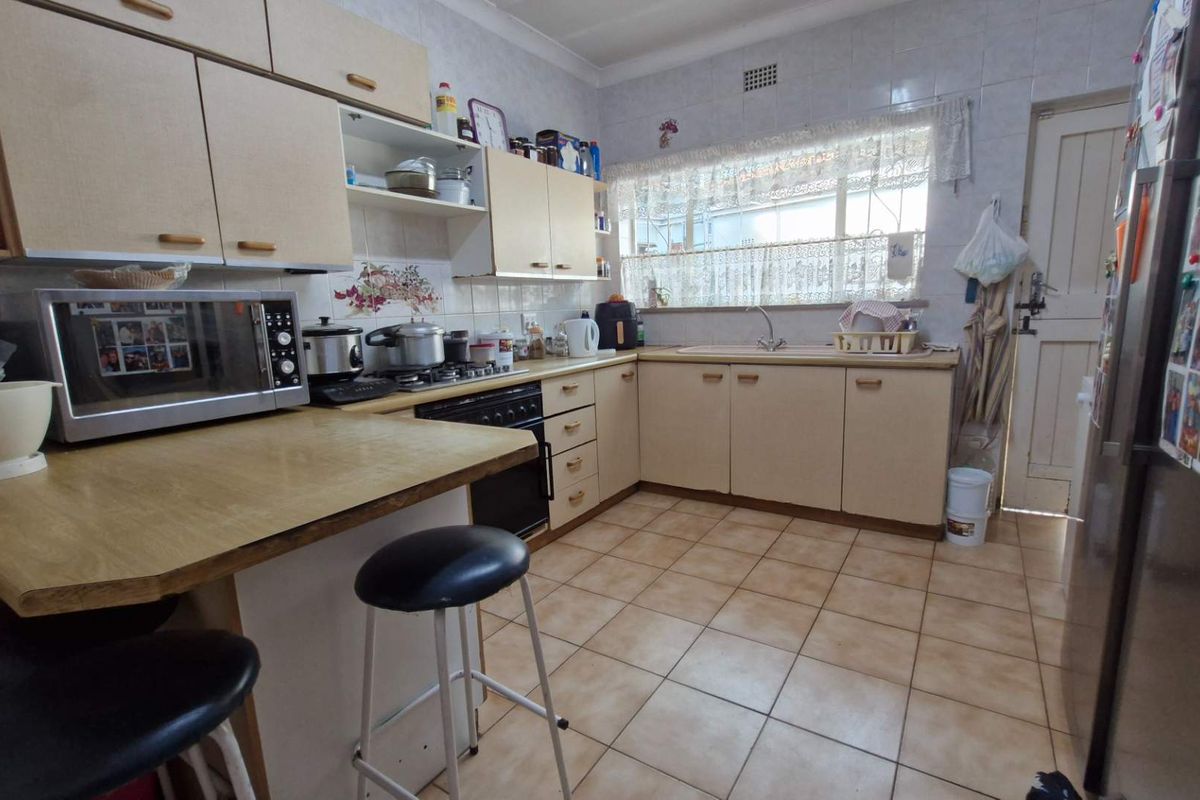 A functional kitchen featuring tiled flooring, ample built-in cabinetry, a gas hob, and a double sink with a tiled backsplash.