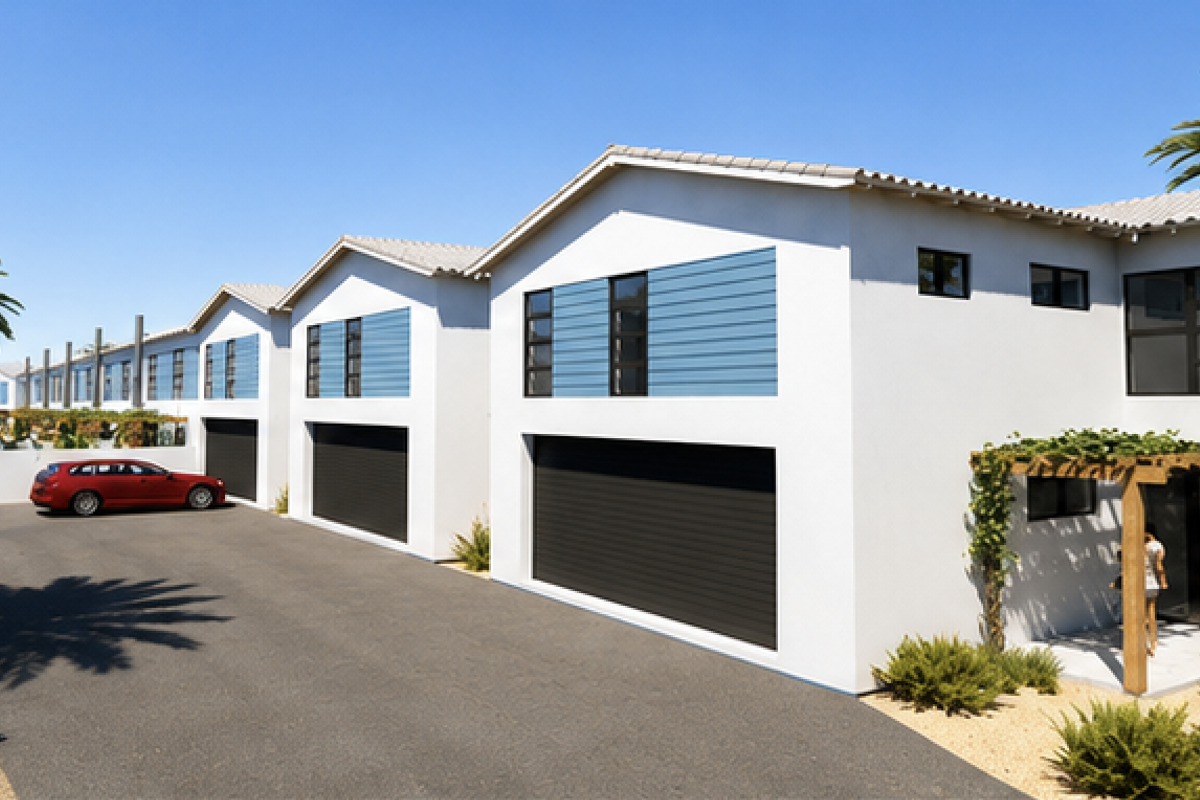 A modern townhouse complex featuring clean white facades, blue accent panels, automated garages, and paved driveway access with landscaped surroundings.