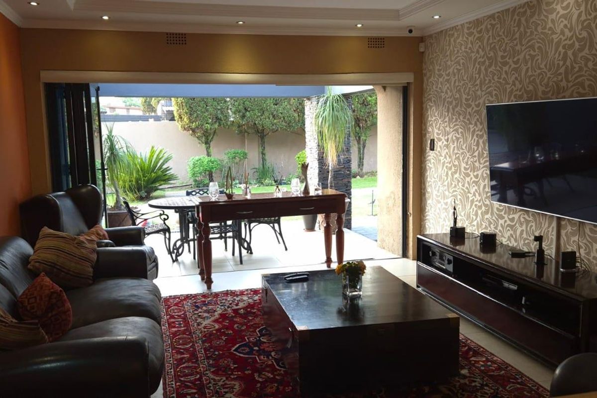 Spacious living room featuring recessed lighting, decorative wallpaper, and large sliding doors that open onto a covered patio and garden area.