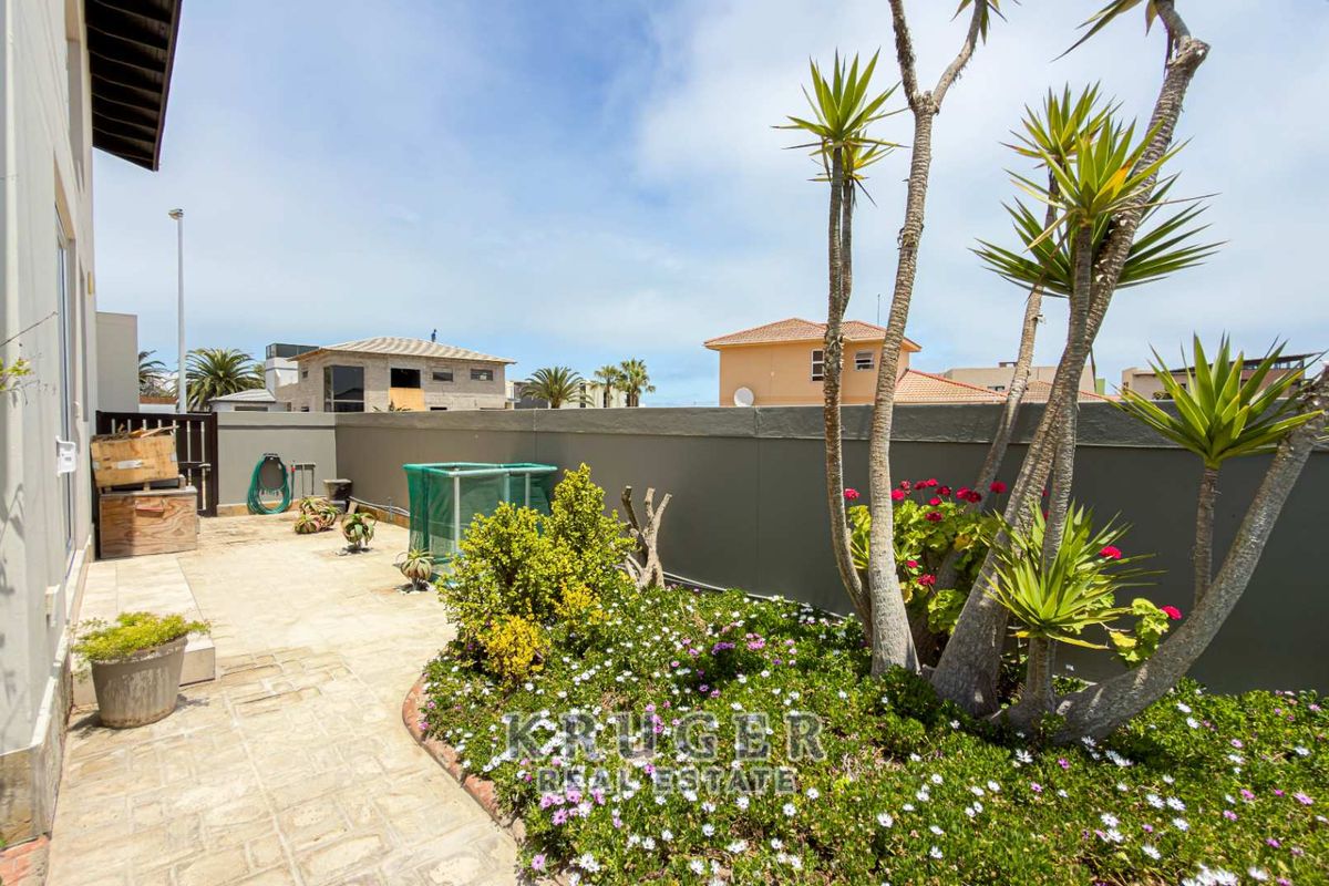 A private rear patio area featuring paved flooring, a landscaped garden bed, and a solid boundary wall for added privacy.