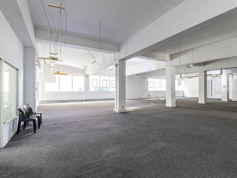 A large, open-plan commercial space featuring exposed concrete columns, beams, and expansive windows, offering a versatile layout for various business or office configurations.