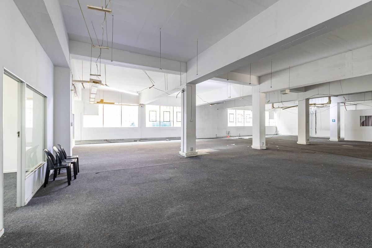 A large, open-plan commercial space featuring exposed concrete columns, beams, and expansive windows, offering a versatile layout for various business or office configurations.