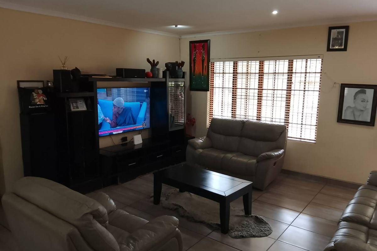 A comfortable living room featuring tiled flooring, recessed downlighting, and large windows fitted with wooden blinds, providing a functional and well-lit space.