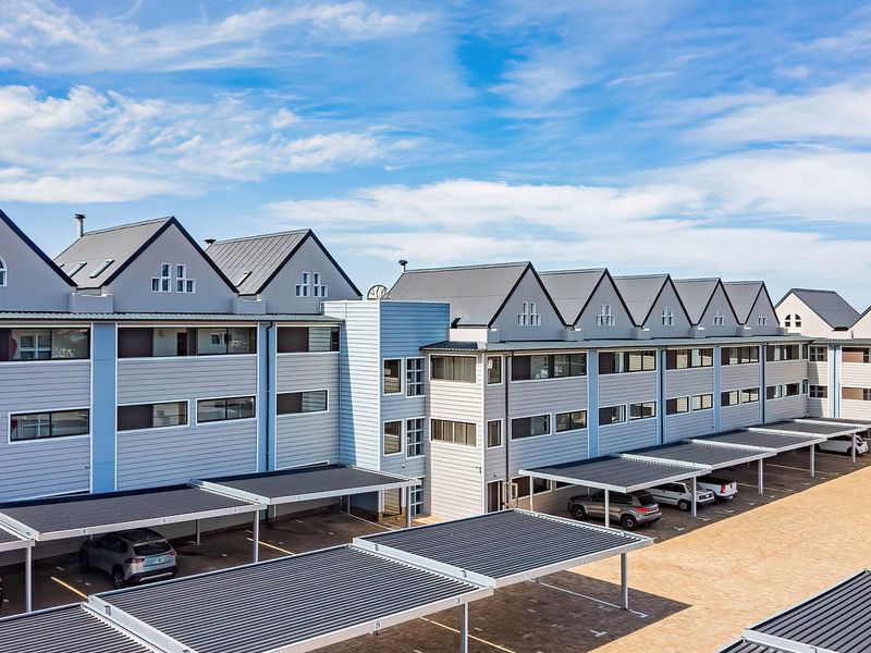 Exterior view of a multi-story apartment complex featuring modern siding, metal roofing, and covered parking bays.