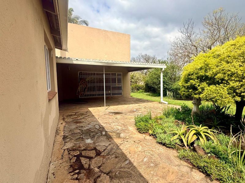 A covered outdoor patio area featuring stone paving and a security gate, providing a functional space for outdoor relaxation and garden access.