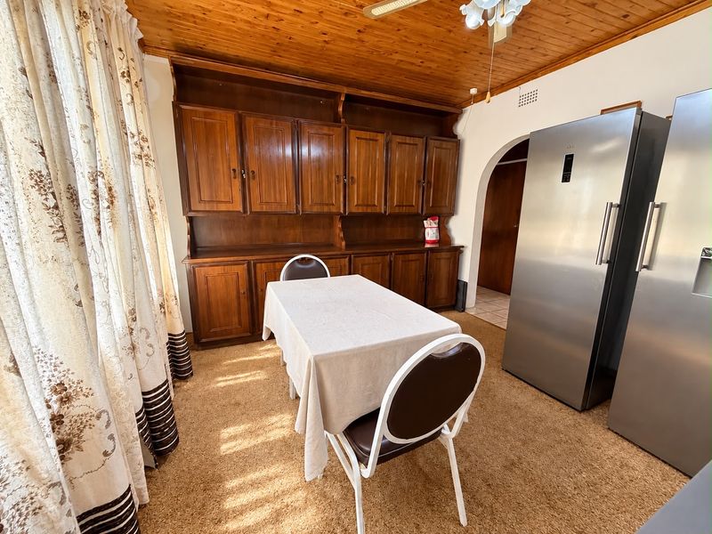 Dining area featuring built-in wooden cabinetry, a warm timber ceiling, and an arched doorway leading to adjacent spaces.
