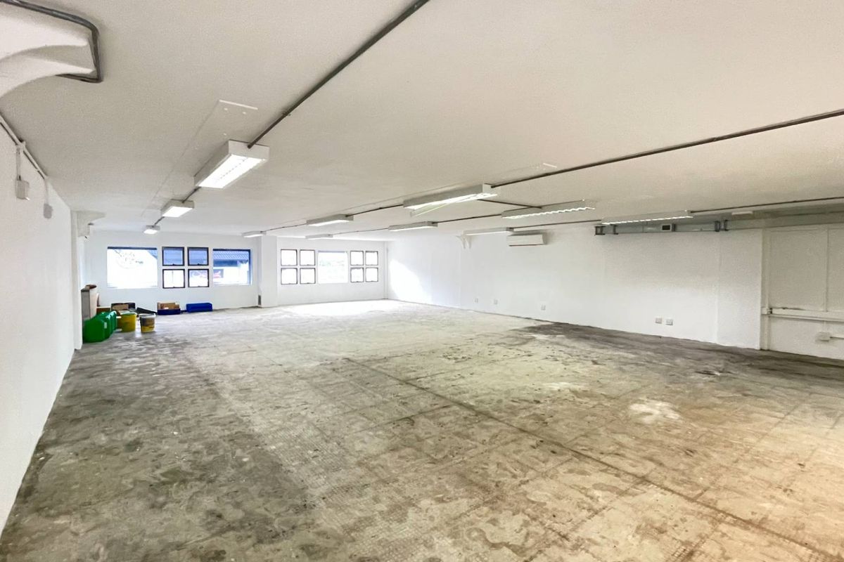 A large, open-plan retail space featuring white walls, fluorescent lighting, air conditioning, and exposed concrete flooring, suitable for various commercial fit-out options.