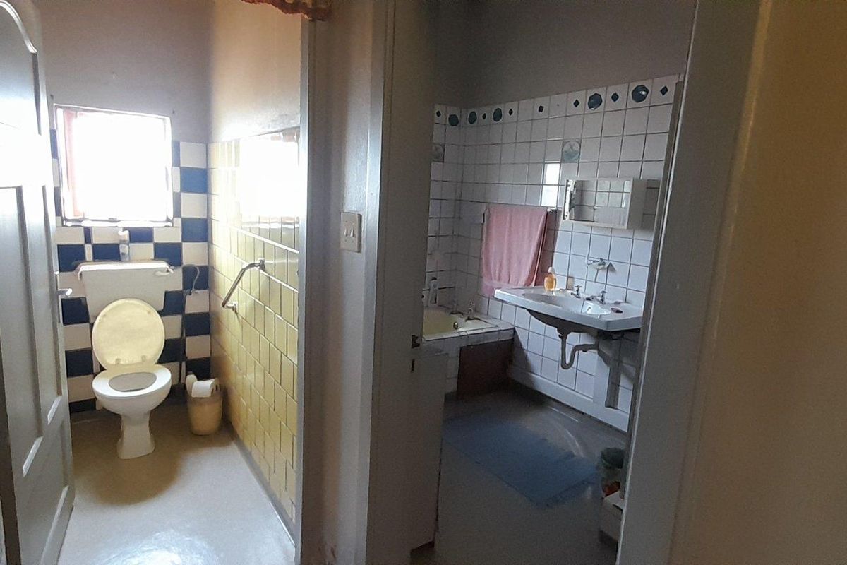 A functional bathroom featuring a separate toilet area and a main bathroom space with a bathtub and wall-mounted basin.
