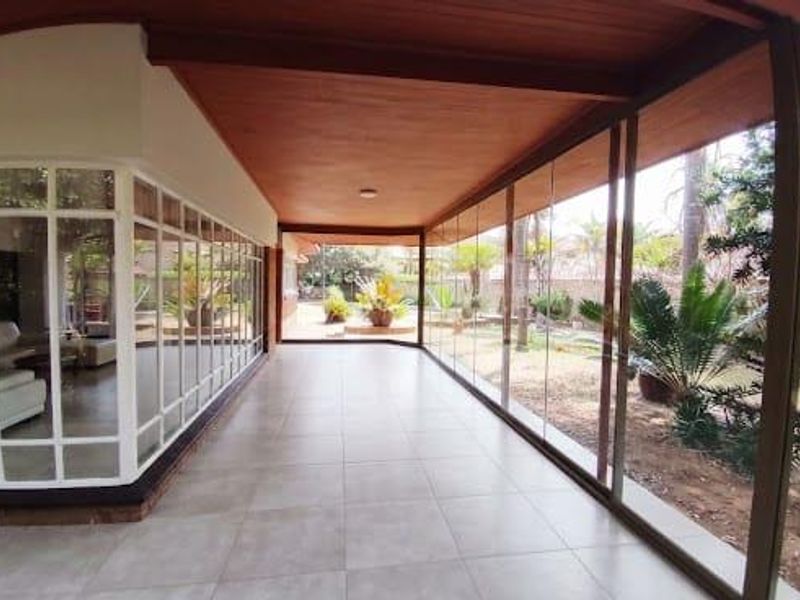 A spacious, covered patio featuring tiled flooring, a timber ceiling, and extensive glass sliding doors that provide a seamless transition to the garden.
