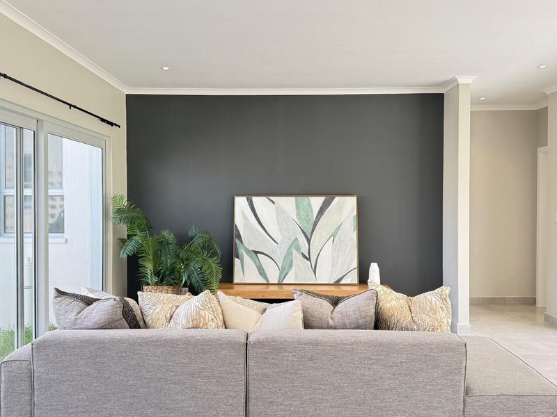 A bright and modern living room featuring a dark accent wall, recessed downlights, and large sliding glass doors providing access to the exterior.