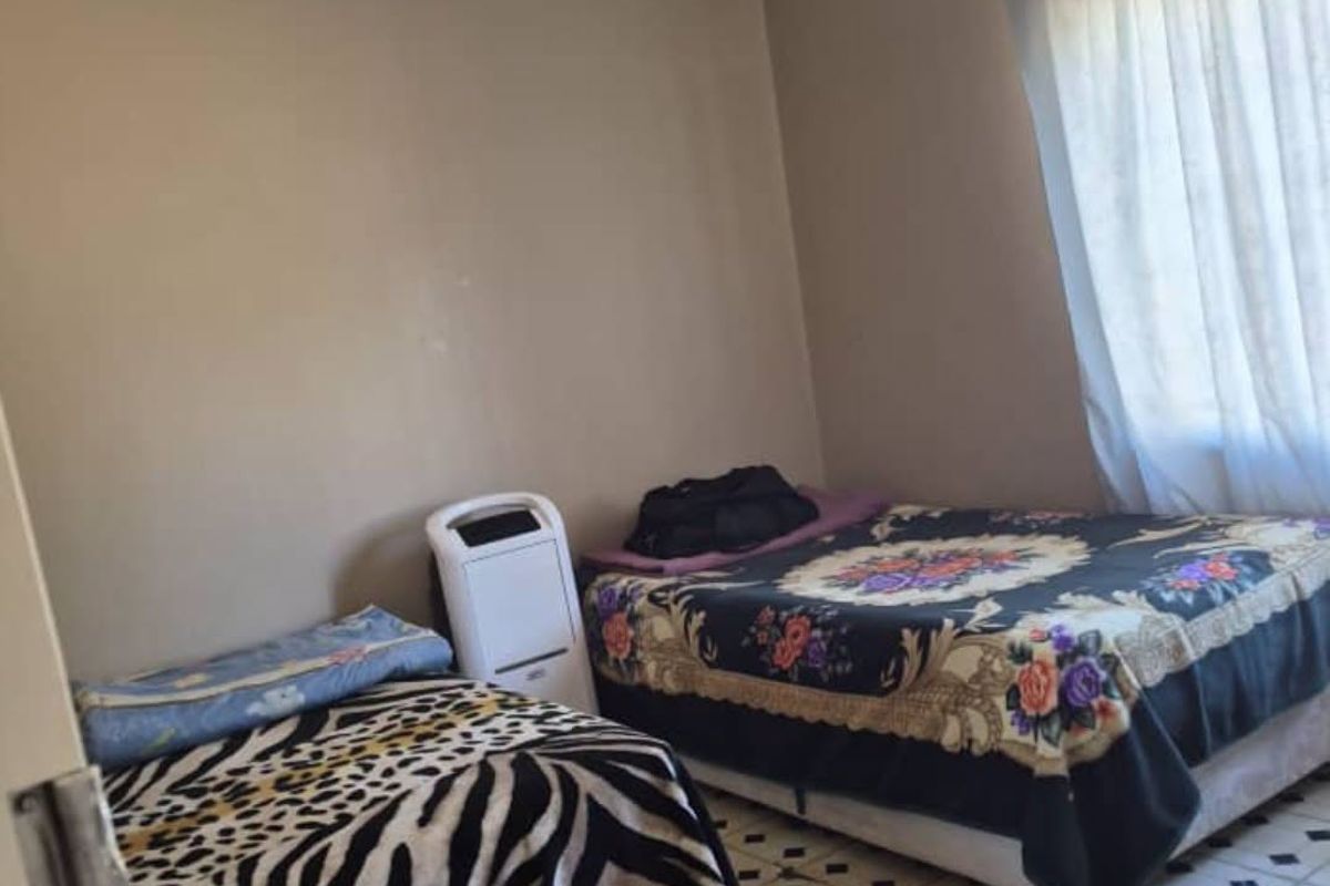 A bedroom featuring tiled flooring and neutral wall paint, offering a functional space that could benefit from cosmetic updates.