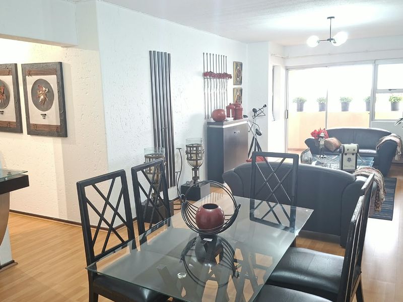 Open plan living and dining area featuring laminate flooring, textured walls, and large sliding glass doors leading to an outdoor balcony space.