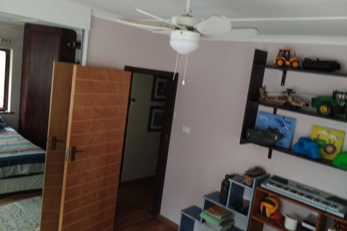 A bedroom featuring laminate flooring, a ceiling fan, and built-in wardrobe storage.