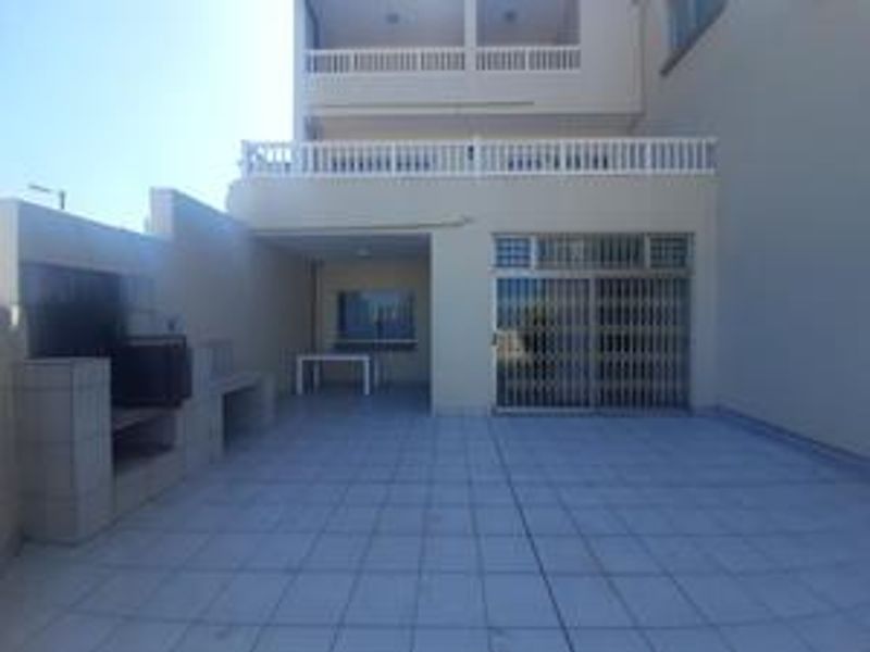 Rear exterior view of the townhouse featuring a paved patio area with a built-in braai and access to the ground floor living space.