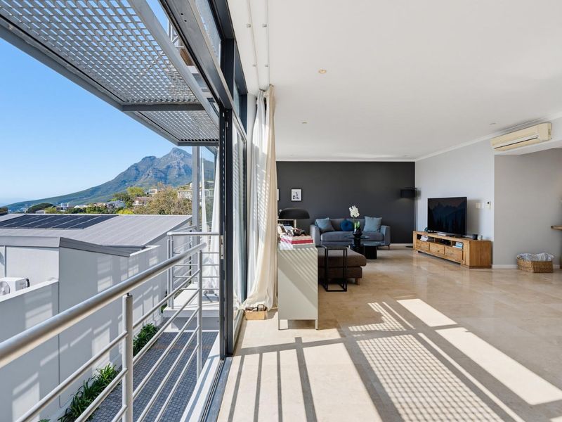 Spacious open-plan living area featuring polished marble floors, large sliding doors opening to a balcony, and mountain views.