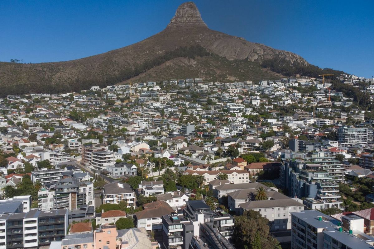 An aerial view of a dense residential neighborhood nestled at the base of a prominent mountain peak.