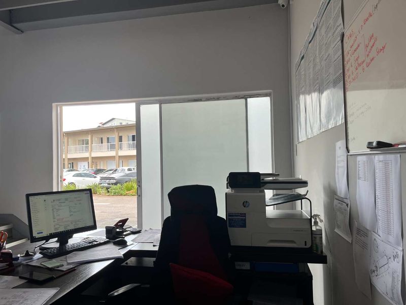 Functional office space featuring exposed ceiling beams and a sliding glass door providing natural light and exterior access.