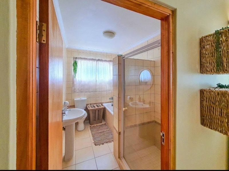 A functional bathroom featuring a pedestal basin, toilet, bathtub, and a separate shower enclosure with tiled finishes throughout.