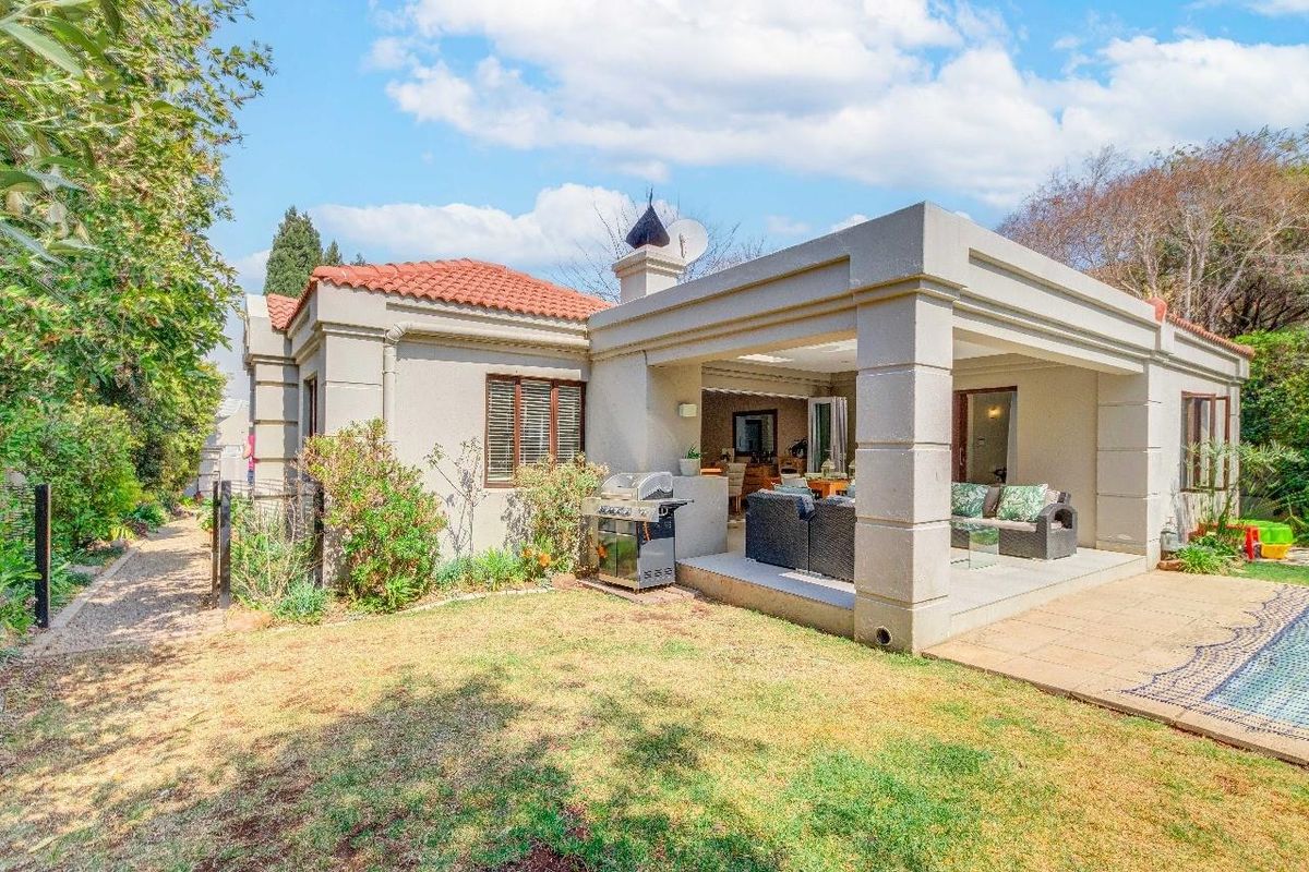 Rear view of the property featuring a covered patio, swimming pool, and well-maintained garden area with classic architectural detailing.
