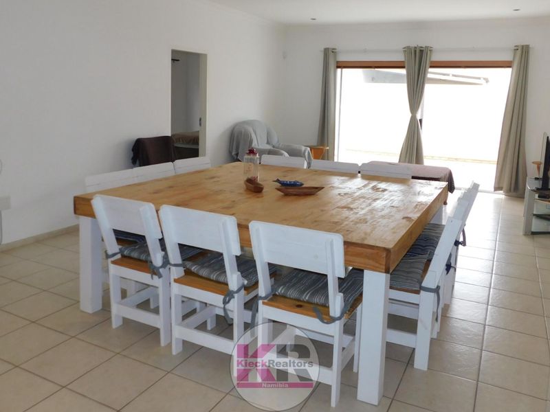 Spacious dining area featuring neutral tiled flooring, recessed lighting, and large sliding glass doors providing access to the outdoor area.