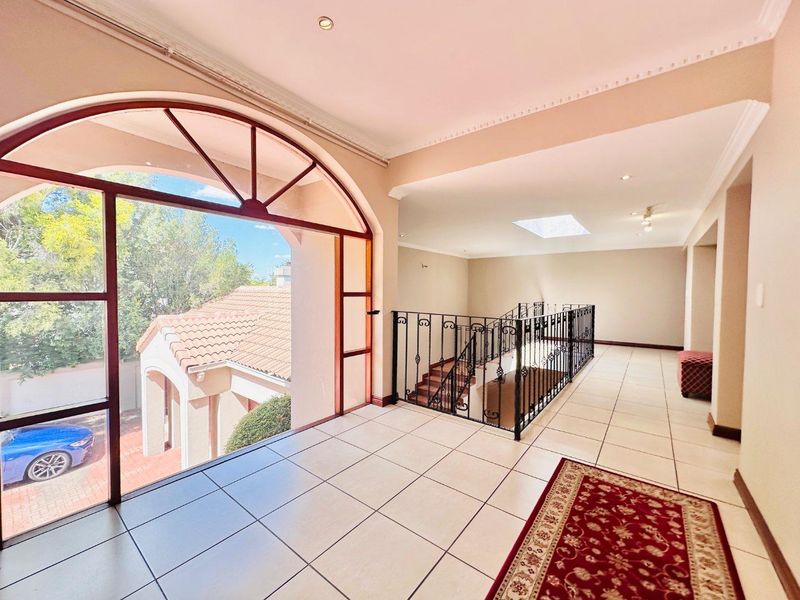Spacious upper-level landing area featuring large arched windows, tiled flooring, and a decorative wrought iron staircase railing overlooking the lower level.