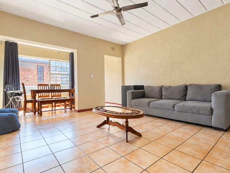 Open plan living and dining area featuring tiled flooring, a ceiling fan, and textured wall finishes, providing a functional and versatile living space.