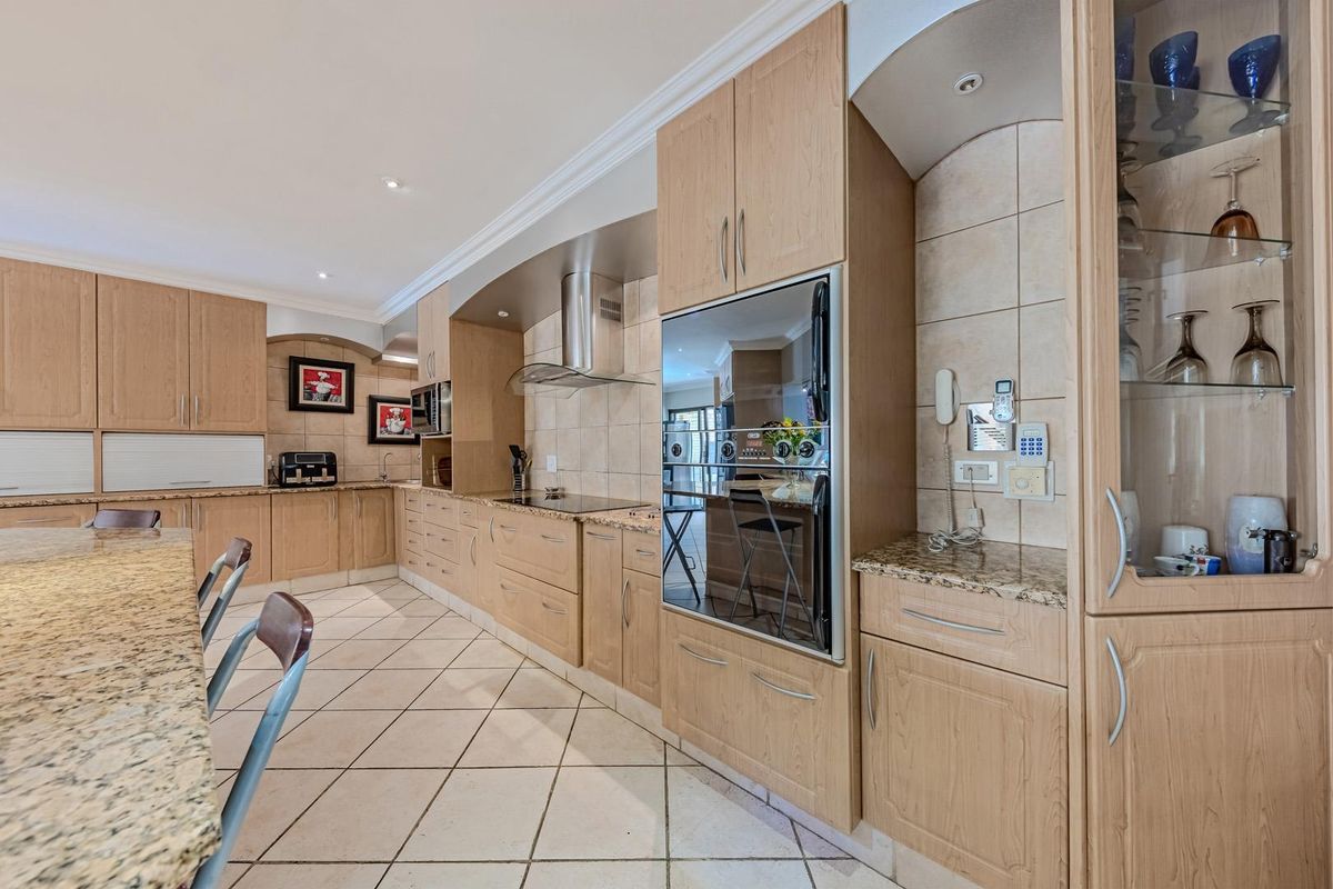 Spacious kitchen featuring light wood cabinetry, granite countertops, built-in appliances, and tiled flooring, offering a functional and well-maintained cooking space.