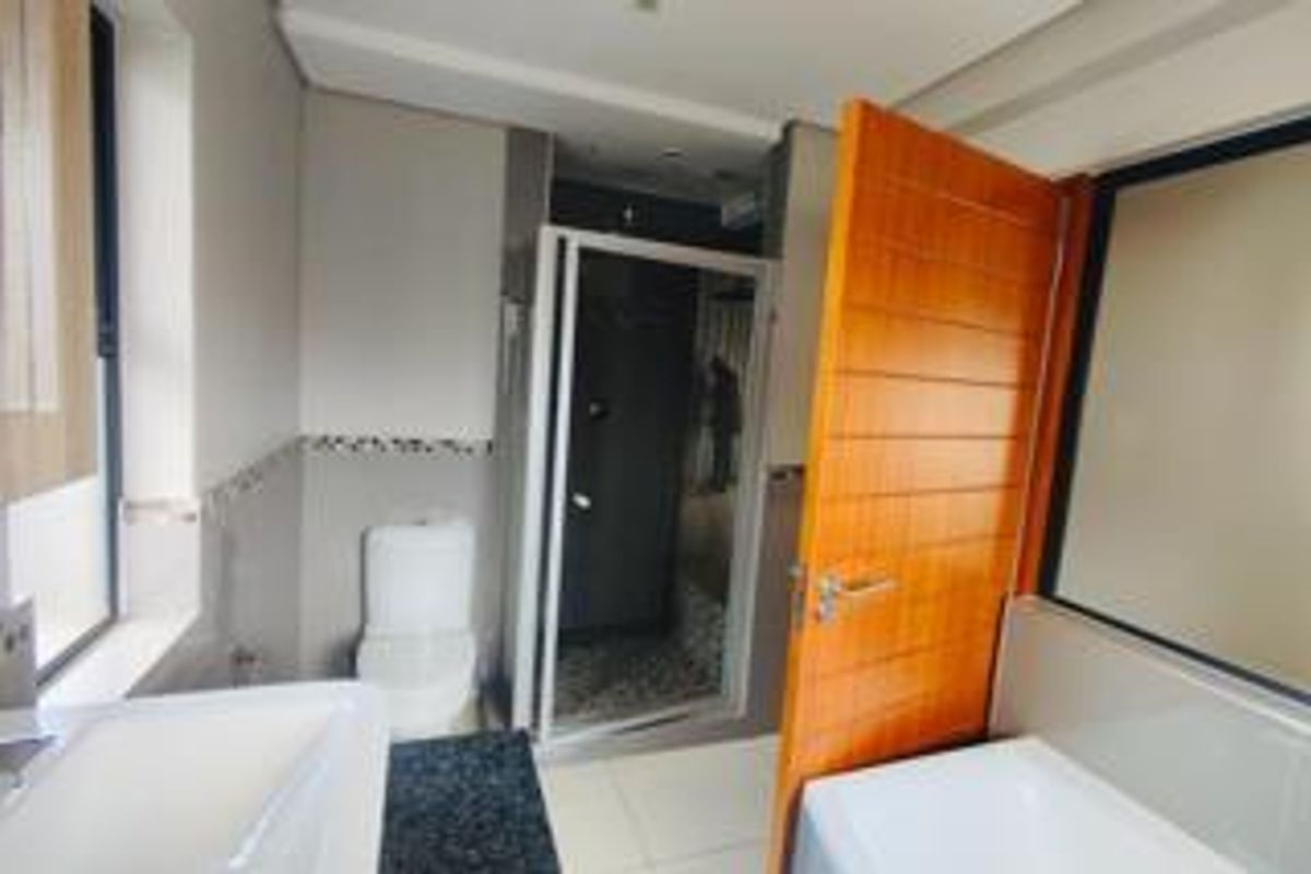 A modern bathroom featuring a shower enclosure, bathtub, vanity basin, and tiled flooring, presented in a clean and functional layout.