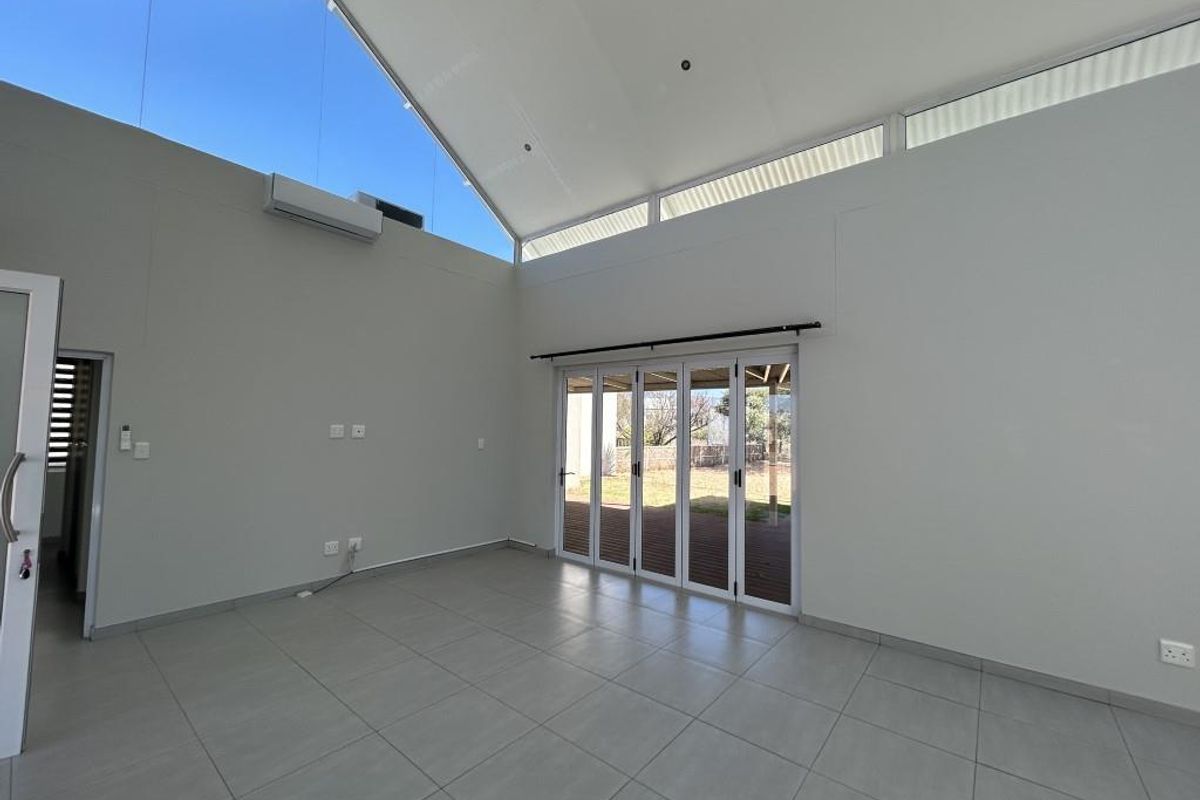 Spacious living area featuring high vaulted ceilings, clerestory windows for natural light, modern tiled flooring, and bi-fold doors opening to the outdoor space.