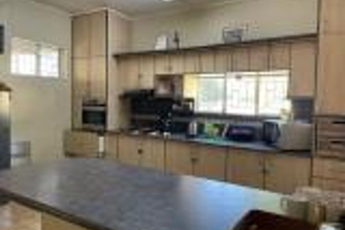 A functional kitchen featuring light wood cabinetry, a central island with a dark countertop, and a built-in oven.