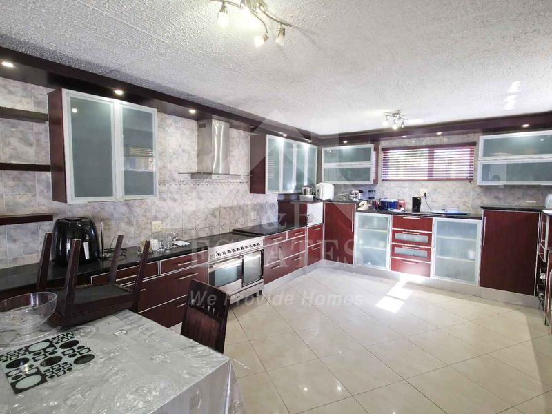 Spacious kitchen featuring extensive built-in cabinetry, tiled backsplash, integrated oven with extractor fan, and polished ceramic tile flooring.