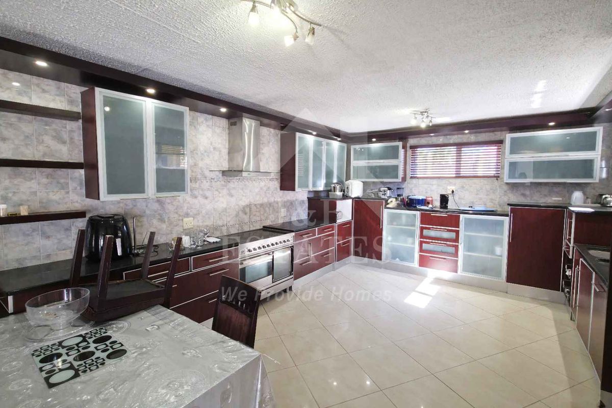 Spacious kitchen featuring extensive built-in cabinetry, tiled backsplash, integrated oven with extractor fan, and polished ceramic tile flooring.