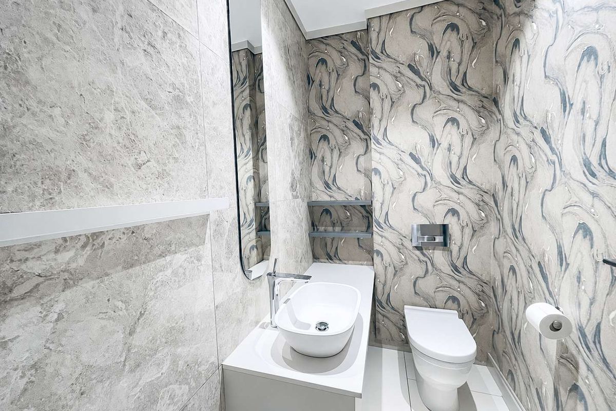 Modern powder room featuring marble-look wall tiles, patterned wallpaper, a sleek vessel sink vanity, and a wall-mounted toilet.