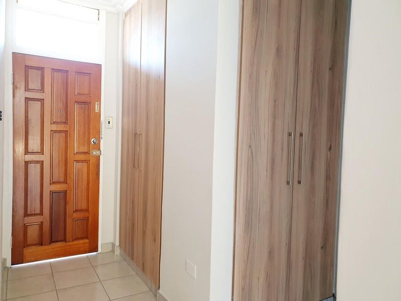 Entrance area featuring tiled flooring and ample built-in cupboard storage with a solid wood front door.