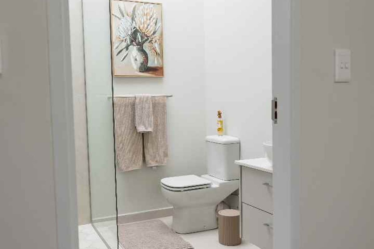 A modern, bright bathroom featuring a skylight, glass shower enclosure, and a sleek vanity cabinet with clean tiled finishes.